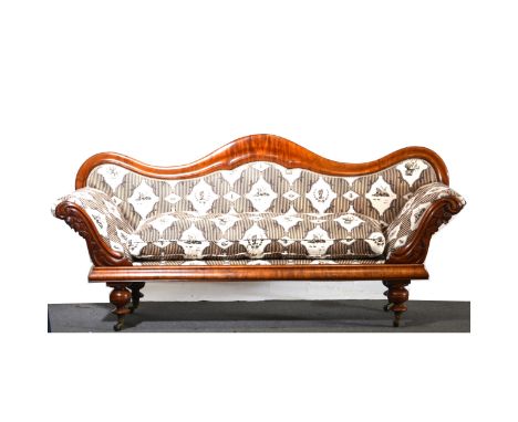 Victorian mahogany sofa, shaped back, carved scrolled arms, turned legs, on casters, French Empire style upholstery with a lo