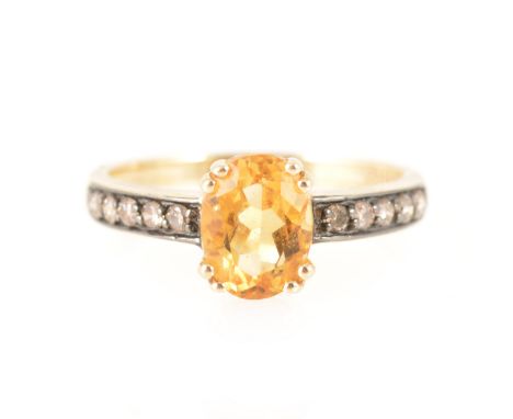 A citrine and chocolate diamond ring, the oval mixed cut citrine 7.8mm x 6mm, four double claw set in a yellow metal mount ma