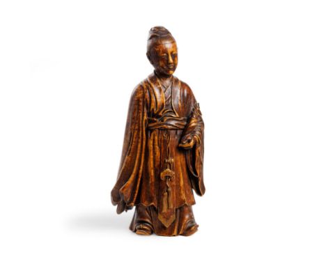 A Chinese wood figure of a scholarQing dynasty, 18th centuryClad in thickly-folded robes and cradling a wrapped scroll in his