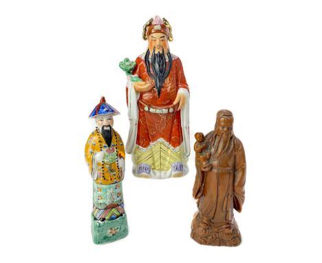 20TH CENTURY CHINESE CERAMIC FIGURES OF FU, LU AND SHOU, two in ceramic and one in carved wood, the tallest 28cm high (3)