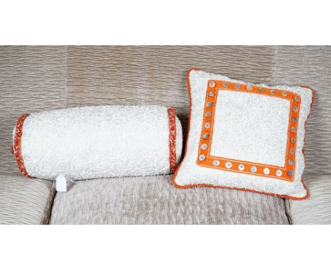 A scrunched cream silk bolster cushion, with braided ends, and another of square shape with a border of mother of pearl butto