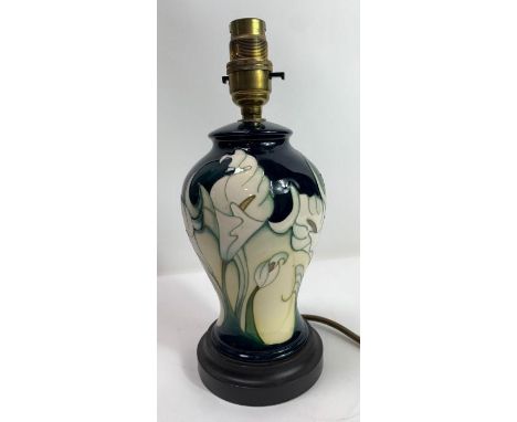 A Moorcoft lamp base of baluster form, tubelined and decorated with white calla lillies on a navy blue and cream ground, on a