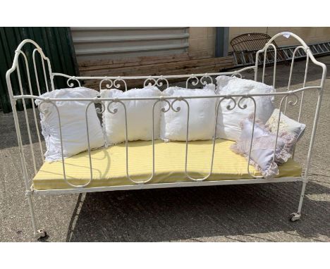 A Victorian white painted metal child's/dolls bed frame, with decorative bent metal design to each side, on four casters, wit