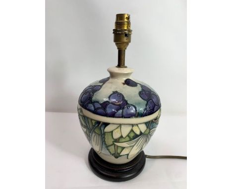 A modern Moorcroft lamp base of short bulbous form, tubelined and decorated in the Juneberries pattern, on a circular mahogan