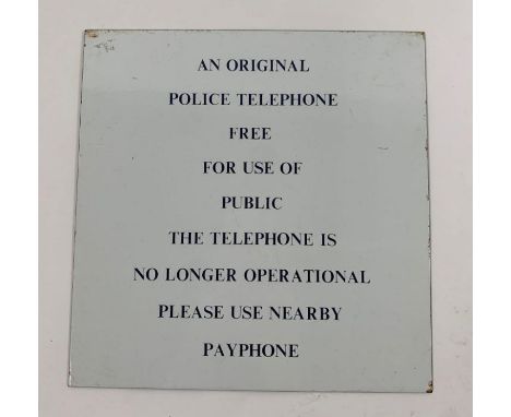 A white enamel sign with navy blue text 'an original police telephone free for use of public the telephone is no longer opera