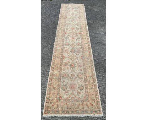 A Middle Eastern wool runner of Persian style pattern with stylised flora and foliage, in pastel shades of cream/green, appro