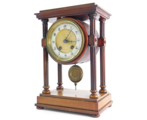 A late 19th/early 20thC French walnut portico clock, with a moulded top, reeded pillars supporting a clock with white enamel 