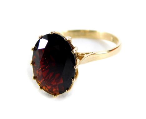 A 9ct gold garnet set dress ring, with oval cut garnet, in a raised claw setting, with pierced design shoulders, Birmingham 1