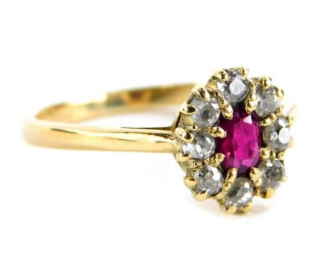 A ruby and diamond cluster ring, with over cut ruby in claw setting, surrounded by round brilliant cut diamonds, on a yellow 