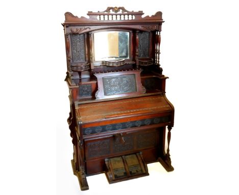 A late 19thC Canadian walnut harmonium,  the elaborate raised back with a central bevelled mirror plate, flanked by carved pa