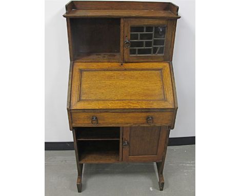 An Arts and Crafts Liberty and Co oak students bureau,  gallery top above a lead glazed cupboard and pigeon hole, fall down f