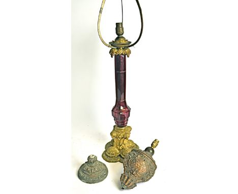 A 19th Century gilt brass lamp base,   with cranberry glass central column, raised on a scrolling quatrefoil base with rams h