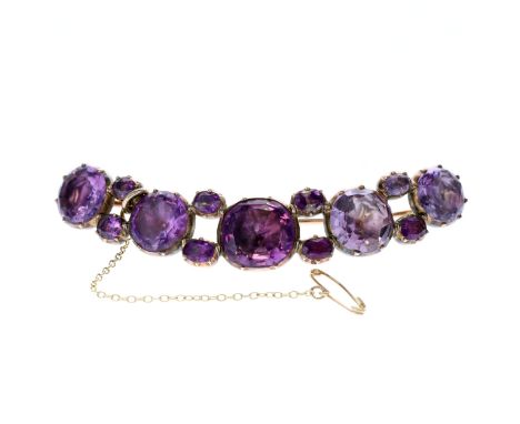 Victorian Gold Amethyst curved bar brooch. Measures approx. 7.6 x 1.4cm, central stone measures approx. 1.4 x 1.4cm. Has been