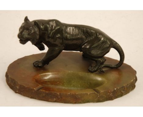 AN EARLY TWENTIETH CENTURY JAPANESE STYLE 'BRONZED' WHITE METAL MODEL TIGER UPON AN OVAL ONYX BASE as an ashtray, 11" (28cm) 