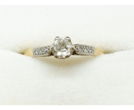 A early 20th century 18ct gold and platinum set solitaire diamond ring on diamond chip shoulders, size K 