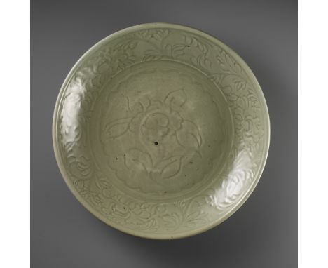 A LARGE AND FINELY CARVED 'PEONY' LONGQUAN CELADON CHARGER, MING DYNASTYChina, 15th-16th century. The broad rounded sides ris