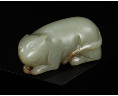 A CELADON AND RUSSET JADE FIGURE OF A MOUSE, QING DYNASTYChina, 1644-1912. Boldly carved, the recumbent mouse rests on its sl