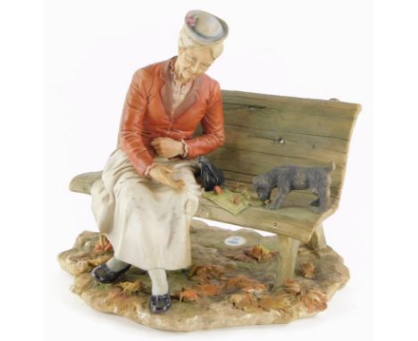 A Capodimonte porcelain figure of an old lady on a bench, beside a terrier puppy, the base decorated with leaves (AF), 24cm w