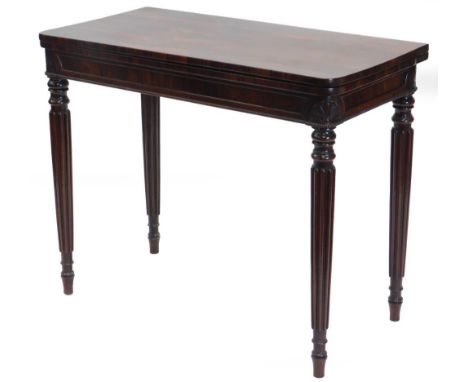 A George IV rosewood card table, the hinged rectangular top with rounded corners, above a panel frieze carved with acanthus t