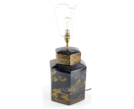 An oriental style pottery lamp base, decorated with river landscapes etc., in black on a gilt ground, to simulate a 19thC tea