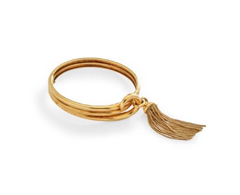 A French 18ct gold bangle of hinged design, scrolling ribbed detail, with tassel pendant(Internal diameter: 5.7cm)