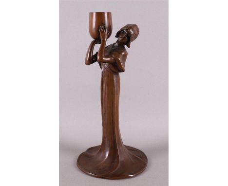 A brown patinated bronze Art Nouveau candlestick of a girl carrying a bowl, circa 1900, height 21.5 cm.