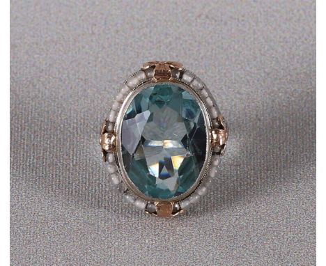 A 10 kt BWG ring with an oval facet cut light blue stone and an entourage of moonstones. Ring size Ø 16.25 mm.