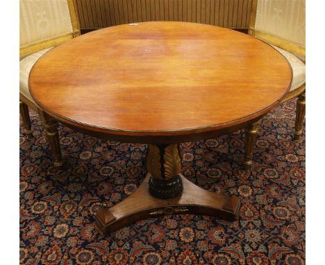 A round mahogany Empire style table, late 19th century. Round top resting on a baluster-shaped trunk with carved leaf motifs,