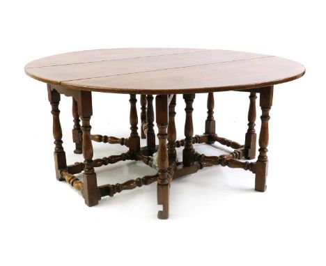 An old reproduction oak gateleg table,the oval top to a double-gate baluster turned and joint base182cm wide157cm deep71cm hi