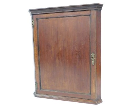 A George III mahogany hanging corner cupboard, with moulded cornice, single panelled door with brass escutcheons and H hinges