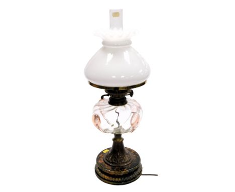 A Victorian oil lamp, with a frosted shade, clear and pink blown glass central reservoir, on a brass column decorated with va