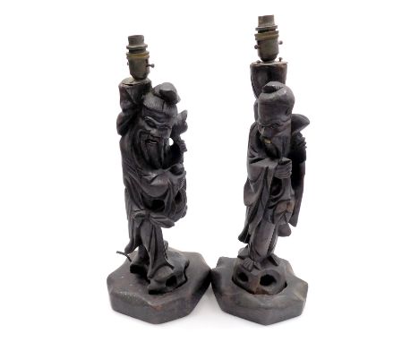 A pair of late 19th/early 20thC oriental carved hardwood lamp bases, each decorated in the form of an immortal with simulated