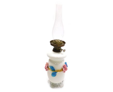 A 20thC milk glass oil lamp, with shaped body raised with glass flowers on a shaped base with plain funnel on metal mount, 58