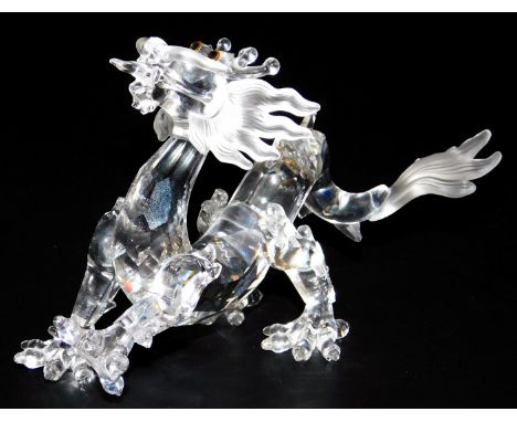 A Swarovski Crystal model of an imperial dragon, raised on a wooden stand, 16cm wide.