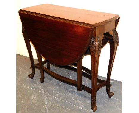 A late Victorian mahogany gate leg dining table, raised on leaf carved slender cabriole legs united by shaped stretchers, 78c