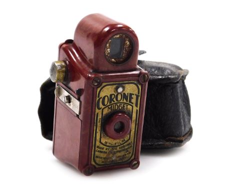 A Coronet Midget camera, with a red and orange faux marble bakelite casing, with a leather sheath, 6.5cm high.