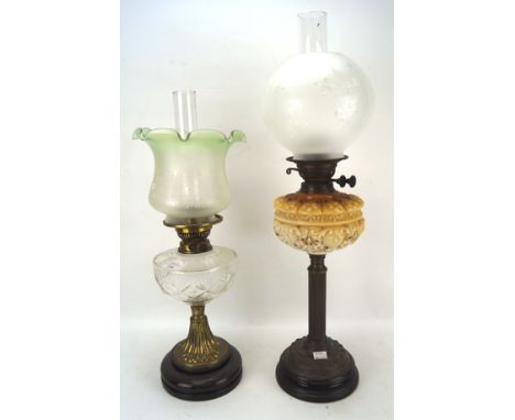 Two late 19th/early 20th century oil lamps, both with cast metal columns mounted on circular ceramic bases, glass reservoirs 