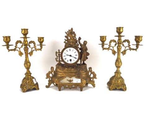 An early 20th century mantel clock and a pair of candlesticks, the clock with Roman numerals to the ceramic dial, the cast me