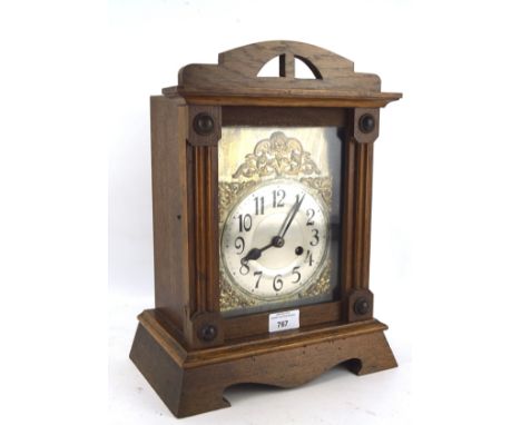 A 20th century oak cased mantel clock, the silvered dial with Arabic numerals, the mount with carved details, H37cm 