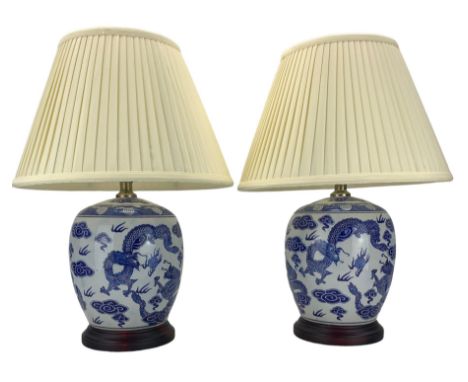 Pair of blue and white ovoid form table lamps, each decorated with dragons chasing the flaming pearl amidst clouds, raised up