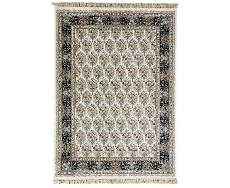 Persian design densely knotted ivory ground carpet, the field decorated with repeating motifs depicting floral urns, guarded 