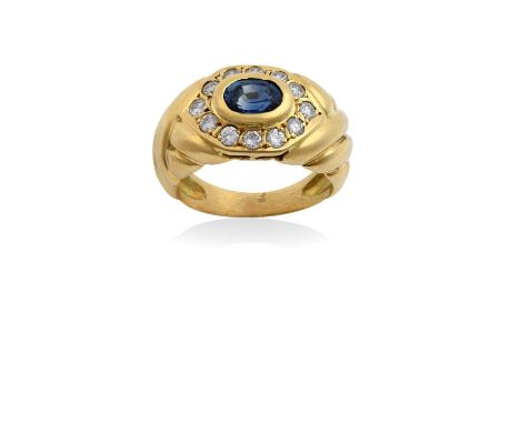 A Sapphire and Diamond Cluster Ringthe oval cut sapphire in a yellow rubbed over setting, within a border of round brilliant 