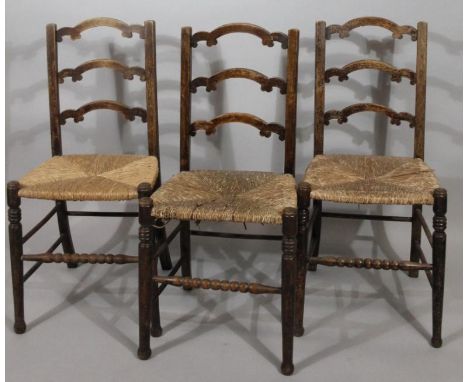 A set of three early 20thC bobbin turned and ladderback chairs, each with rush seats and ring turned front supports, 90cm hig