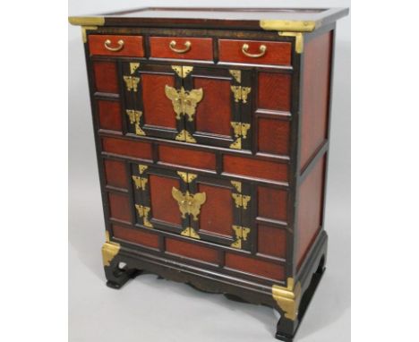 A modern oriental design hardwood cabinet, the rectangular overhanging top raised above an arrangement of drawers and cupboar