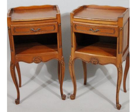 A pair of mid 20thC French bedside cabinets, each with three part galleried tops above a frieze drawer and open shelf on carv