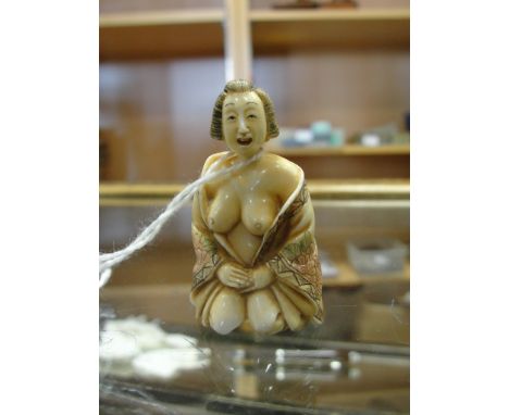 An ivory netsuke meiji period depicting a kneeling bare breasted woman 