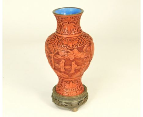 CINNABAR. A Chinese cinnabar vase with blue enamel interior &amp; base, on stand. Height 20cm.