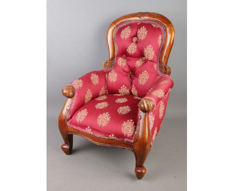An upholstered button back child's/dolls chair featuring carved floral motif.  