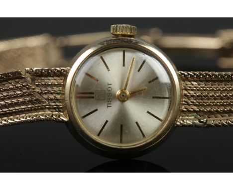 A ladies 9ct Gold Tissot manual wind wristwatch. With silvered dial and baton markers. Stamped to the side of the case and to