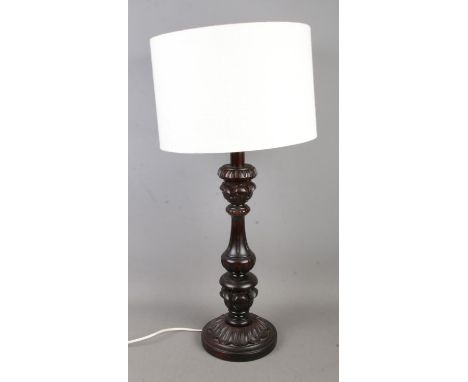 A decorative carved table lamp with cream fabric shade.  